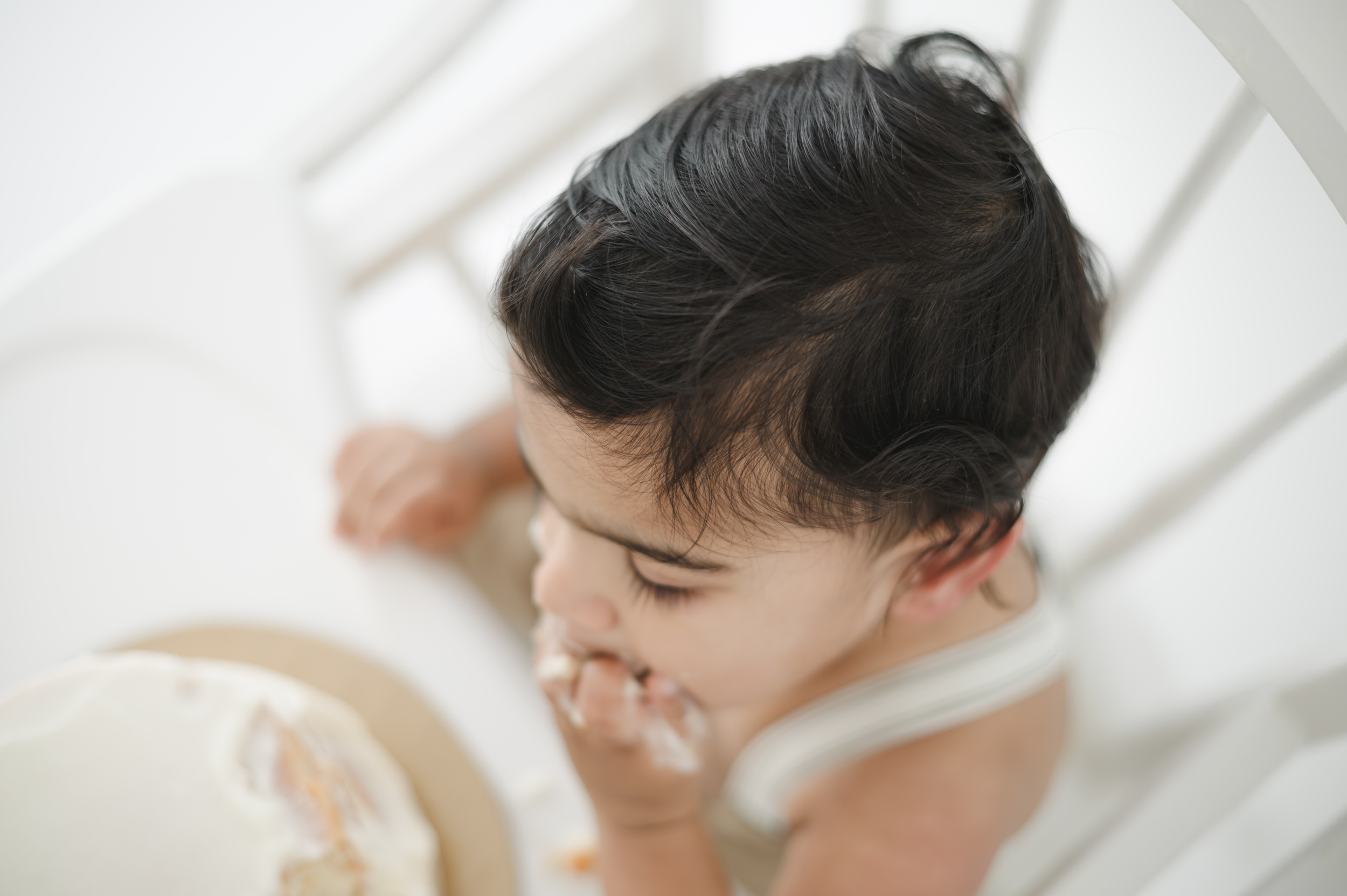 A look down at a happy baby eating a cake in a high chair after some kids cooking classes in austin
