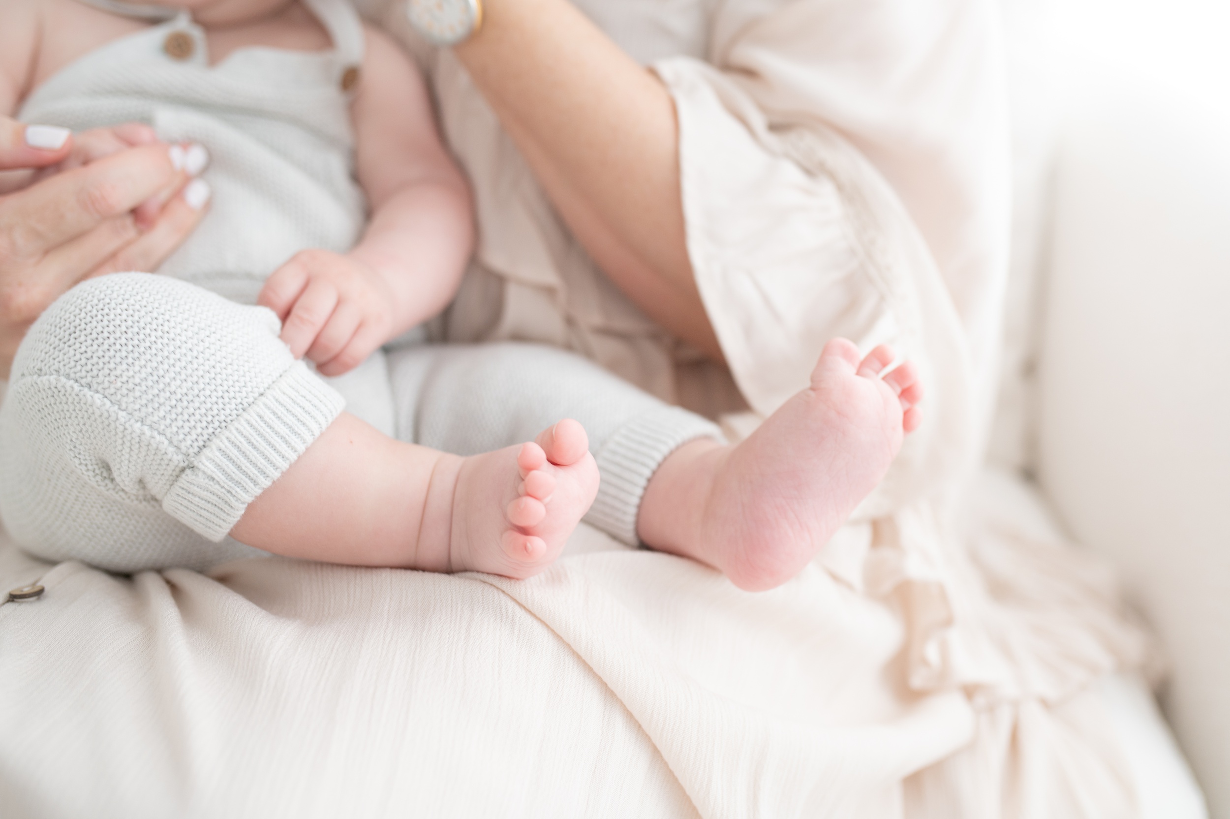 Details of a baby's feet while sitting in mom's lap