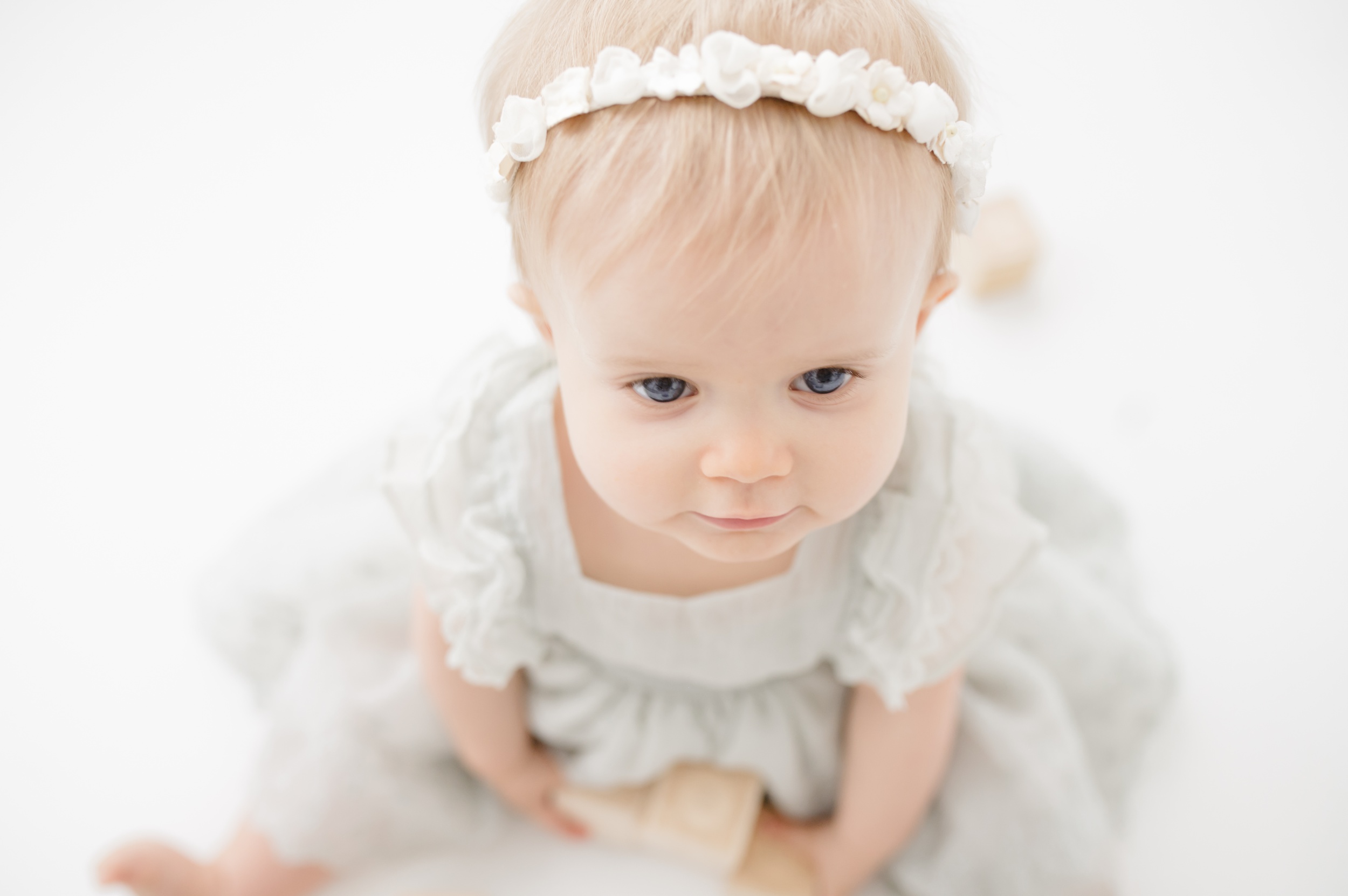 A closeup of a baby girl's head with a white flower headband